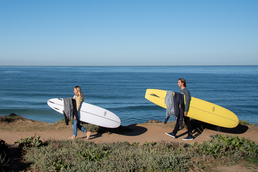 beginner surfers with surfboards walking to the beach to learn how to surf