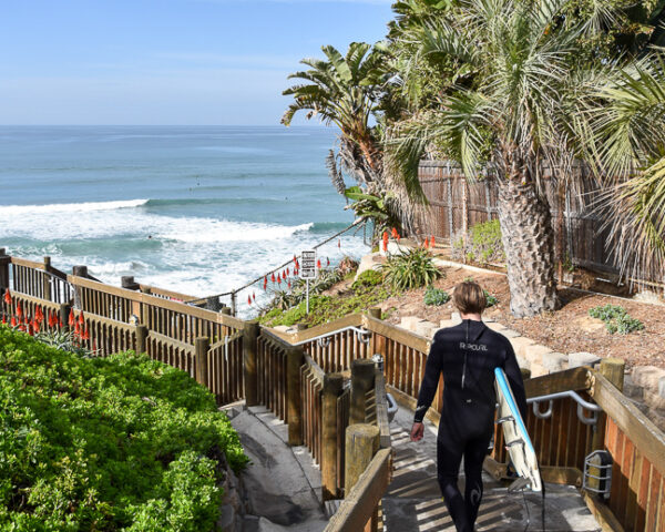 california-surf-retreat guy carrying surfboard down stairs at d st encinitas california