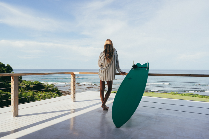 costa-rica-surf-trips-made-easy girl with surfboard on oceanview balcony
