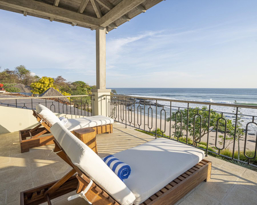oceanfront terrace with wooden lounge chairs and stunning beach view under a shaded canopy