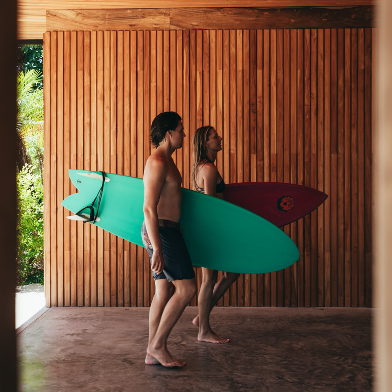 surfers walking into villa carrying surfboards