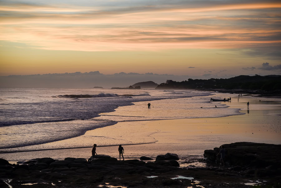 Sunset beach view with waves and silhouettes