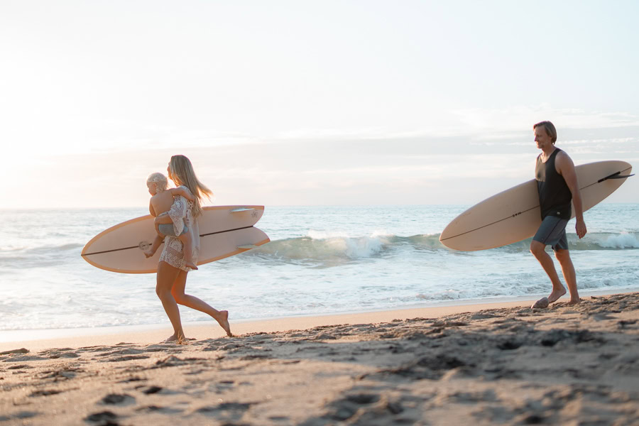 Susurros del Corazon Review / parents and child enjoying beachside with surfboards