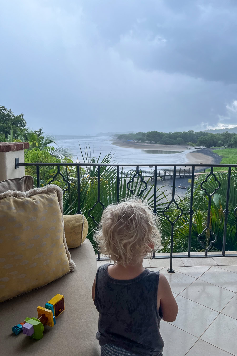 Child enjoying rainy ocean view from a balcony