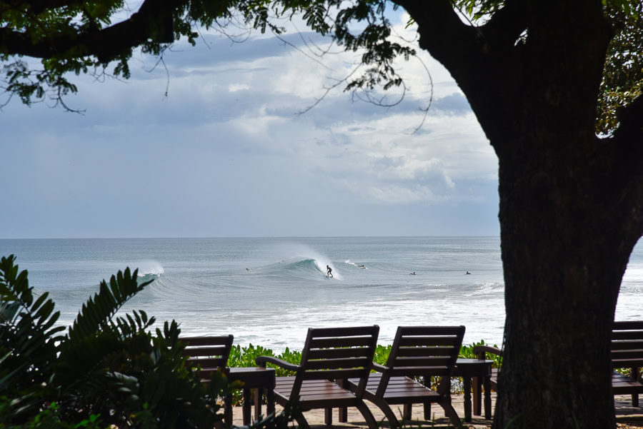 Oceanfront lounge chairs overlooking waves and surfer