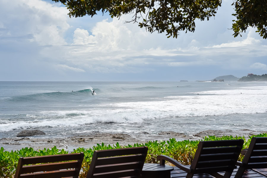 Oceanfront lounge chairs overlooking waves and surfer