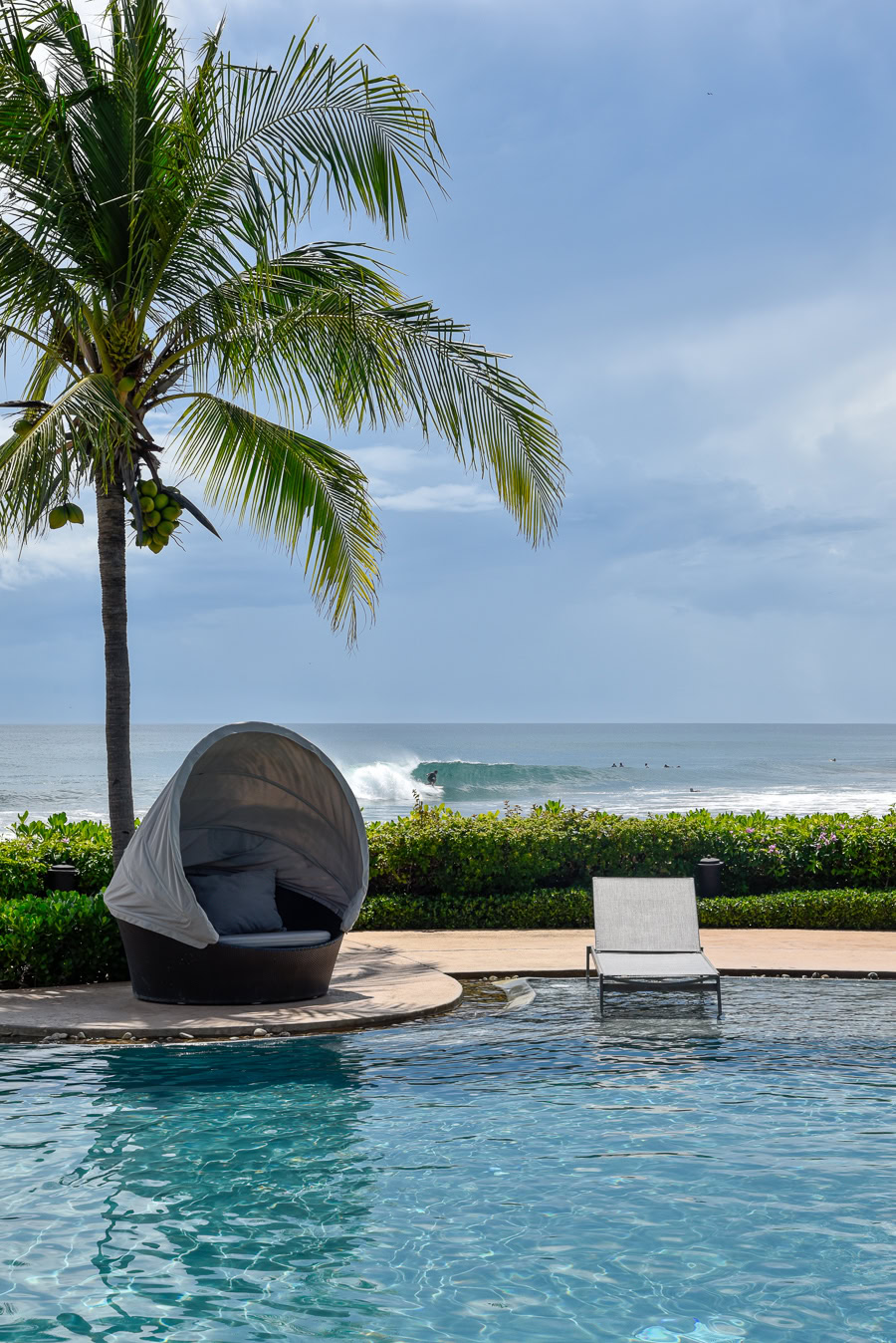 Poolside lounge with ocean views and surfing waves.