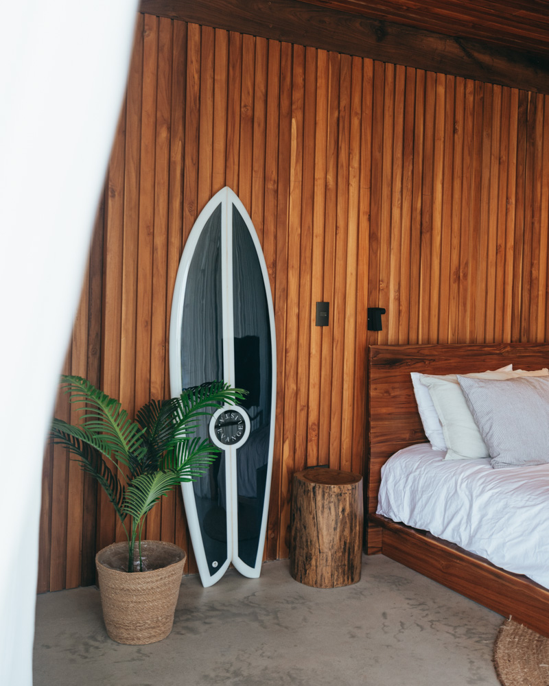 slick black and white fish surfboard against wall by bed