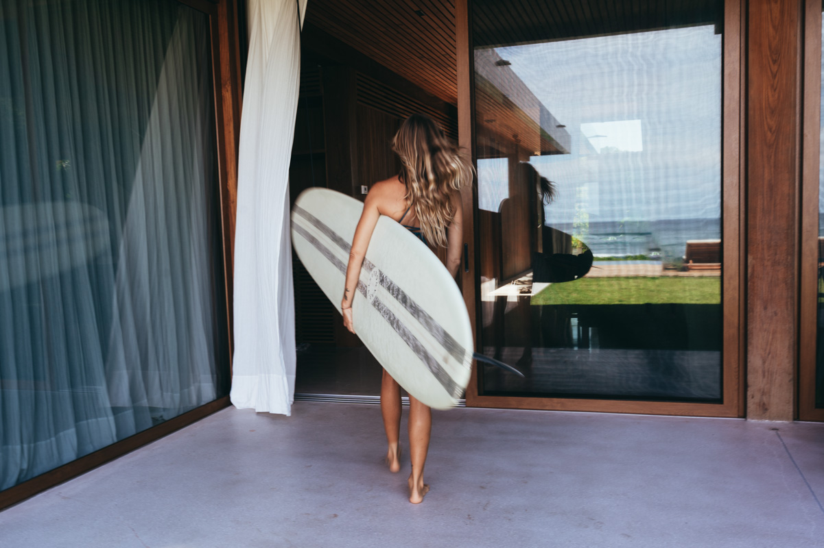 girl carrying longboard into luxe villa