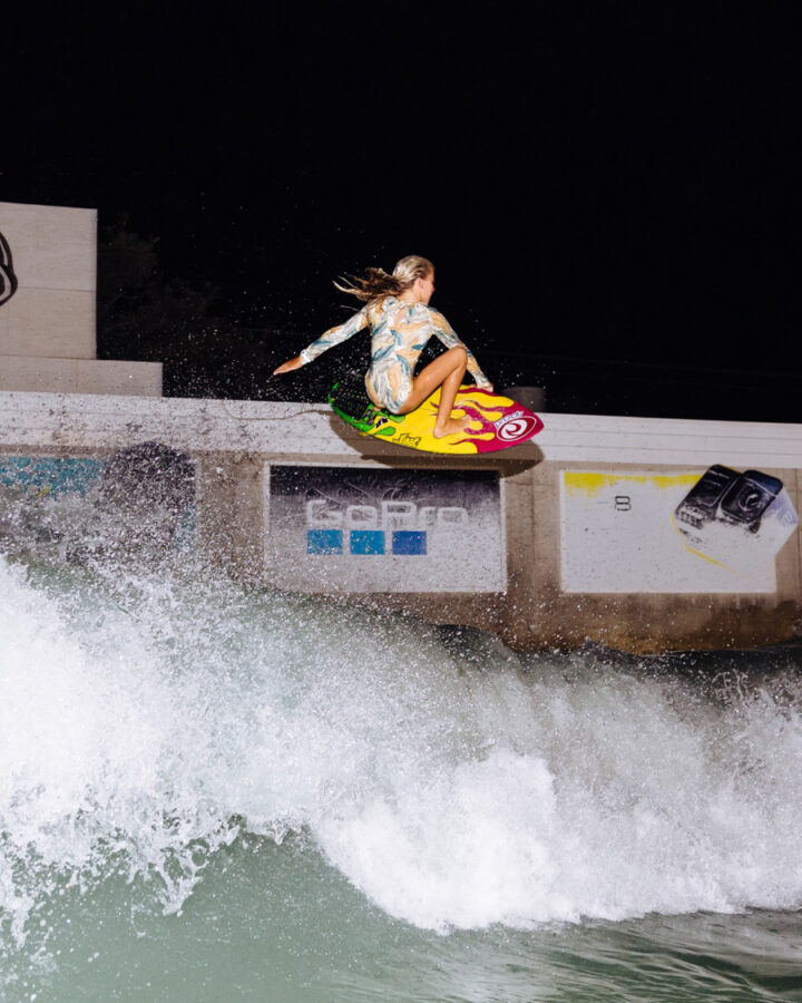 girl surfer performing an air - wearing surf suit by surf brand rip curl