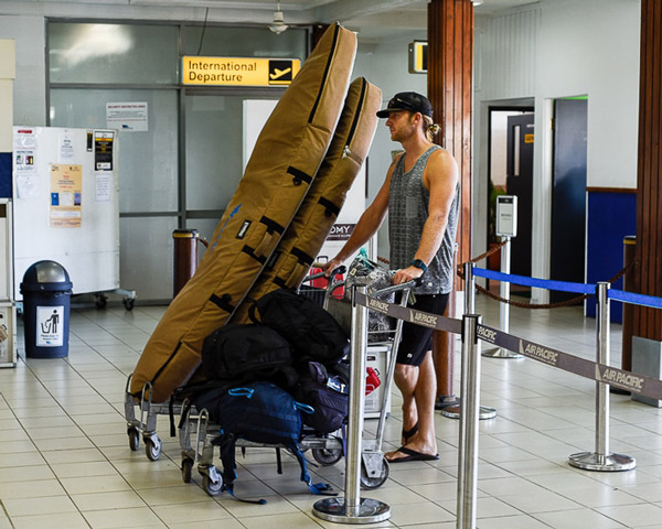 surfer with surfboard bags at airport