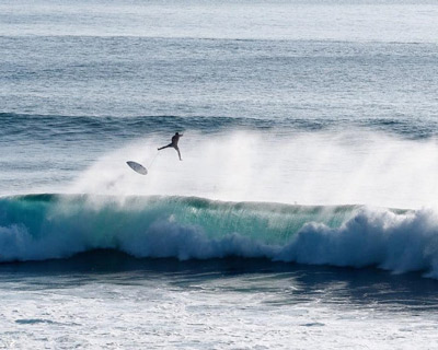 image of surfer launching off closeout wave